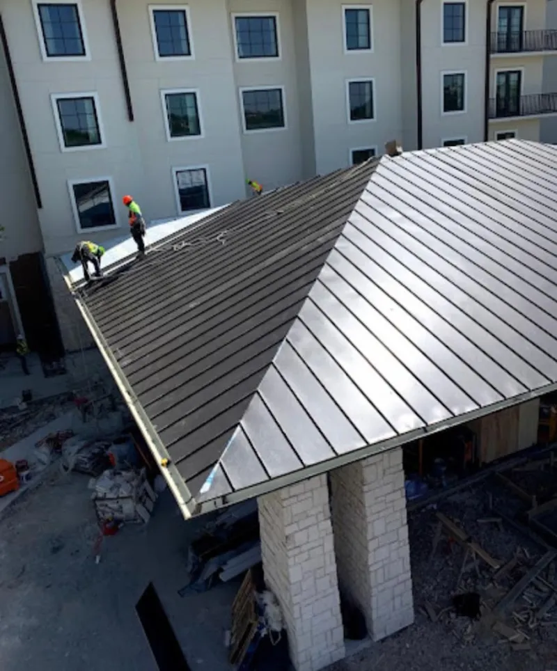 Crew installing standing seam metal roof panels on a commercial project in Fergus Falls